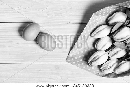 Easter Is Coming. Colorful Bright Eggs And Bouquet Fresh Tulip Flowers On Yellow Background Top View