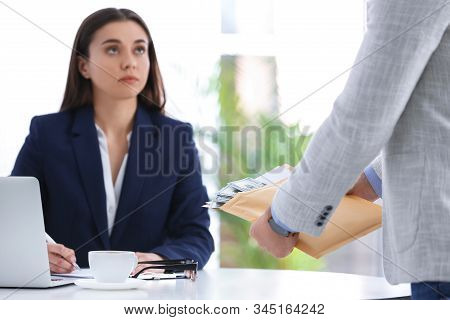 Man Offering Bribe To Businesswoman At Table In Office