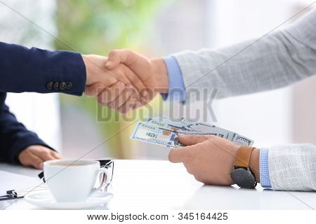 Man Shaking Hands With Woman And Offering Bribe At Table In Office