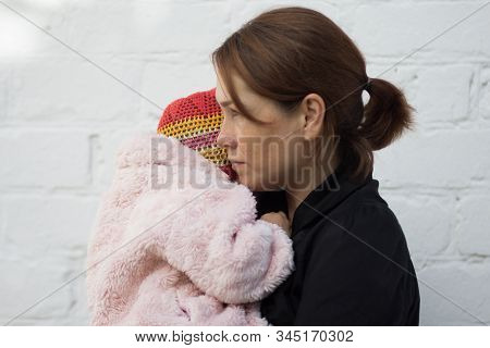 Caucasian Middle Aged Woman Holding On Hands Two Years Old Child And Looking Aside With Anger On Whi