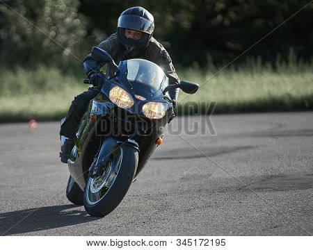 30-09-2019 Riga, Latvia. Motorcyclist On A Black Sports Motorcycle Rides On The Asphalt Ground