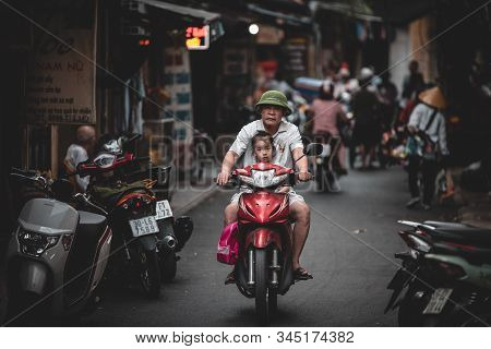 Hanoi, Vietnam - 18th October 2019: An Old Man Rides A Scooter Through The Back Streets Of Vietnam W