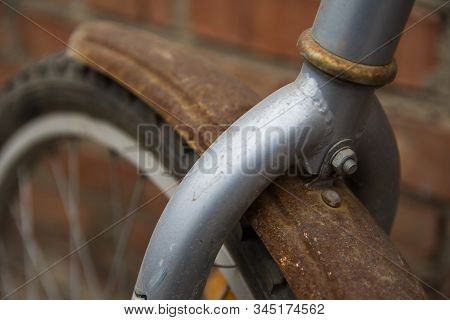 Retro And Vintage Concept. Closeup Shot Of Front Wheel Of An Old Rusty And Dirty Bisycle Which Is St