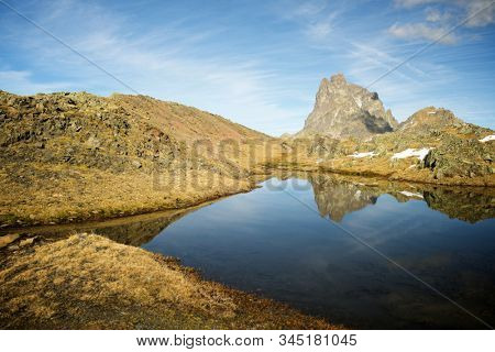 Midi Dossau Peak reflected in a lake. Ossau Valley, Pyrenees National Park, Pyrenees, France.