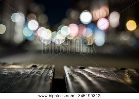 Blurred Background Of A Bridge And Sharpness In Paving Of A Shopping City With Bokeh City Lights