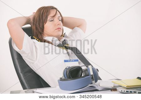 Overworked woman pilot wearing uniform with epaulettes resting or sleeping in briefing room