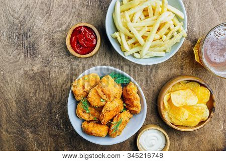 Table Fof Tasty Snacks And Beer Prepared For Watching Sports On Tv. Wooden Background. Top View. Fla