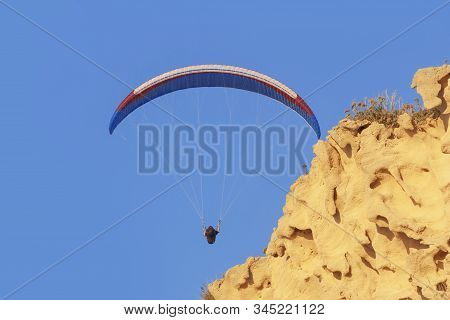 Paraglider Blue Sky And Yellow Sandstone Cliff