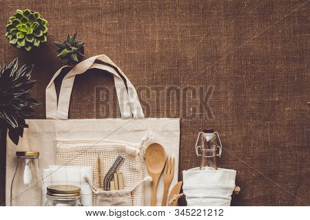 Collection of various succulent plants and Mesh market bag with bamboo cutlery, reusable bottles and eco cotton bags on wooden background
