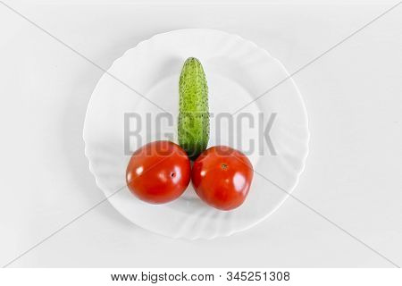 Red Ripe Juicy Tomatoes And Green Cucumber On A White Plate. The Phallic Image Of Natural Components