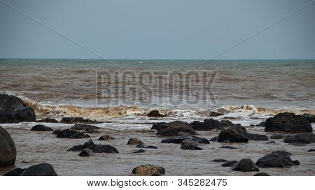 Fierce Waves On The Beach That Hit The Black Coral With Selective Focus.