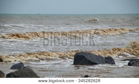 Fierce Waves On The Beach That Hit The Black Coral With Selective Focus.
