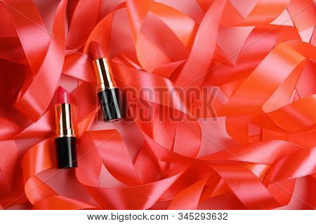 Lipsticks On Pink Ribbons Background Top View. Rouge Lip Gloss Tubes Mock Up From Above. Cosmetics A