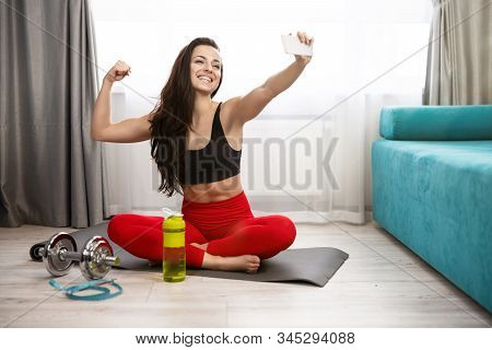 Young Fit Beautiful Woman In Sportwear Doing Selfie On Her Smartphone During Daily Home Workout On T
