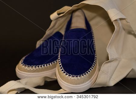 On Black Background Of The Shopping Bag, Shopper, Of Beige Cloth And Blue Slipons Of Suede. Street F