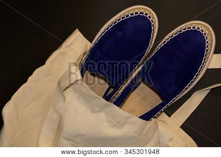 On Black Background Of The Shopping Bag, Shopper, Of Beige Cloth And Blue Slipons Of Suede. Street F
