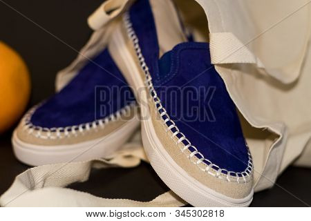 On Black Background Of The Shopping Bag, Shopper, Of Beige Cloth And Blue Slipons Of Suede. Street F