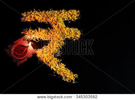Top View Of Clay Lamp And Indian Rupee Sign Made By Rose Petals On Black Background With Copy Space.