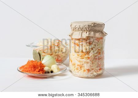 Homemade Sauerkraut With Carrots In A Glass Jar And Bowl On A White Wooden Background. Fermented Foo