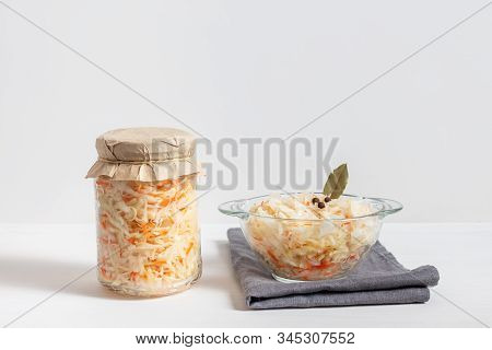 Homemade Sauerkraut With Carrots In A Glass Jar And Bowl On A White Wooden Background. Fermented Foo