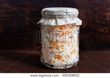Homemade Sauerkraut. Fermented Food. Sauerkraut With Carrots In A Glass Jar On A Dark Wooden Backgro