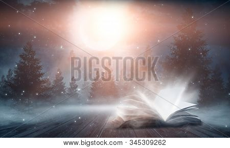 Open Book Magic. Dark Background Magic. An Open Book On A Wooden Table Under The Night Sky Against A