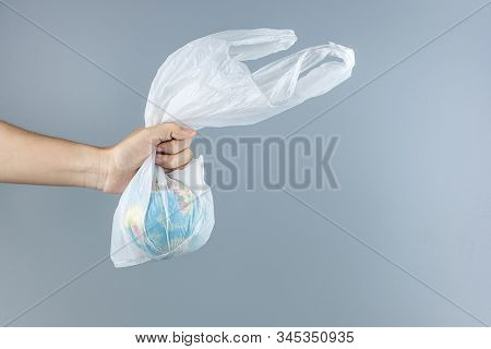 Man Holding Plastic Bag And Globe Inside Against Gray Background With Copy Space For Text. Environme