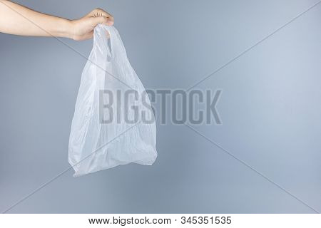 Man Holding Plastic Bag Against Gray Background With Copy Space For Text. Environmental Protection, 