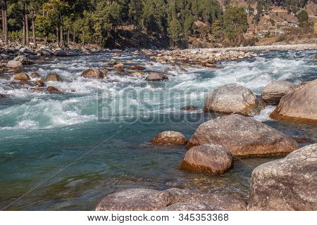 A Small Creek Flowing Through The Valleys Of The Himalayan Mountains With Big Rocks And Pebbles