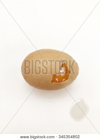 One Raw Egg Is Cracked On A White Table.