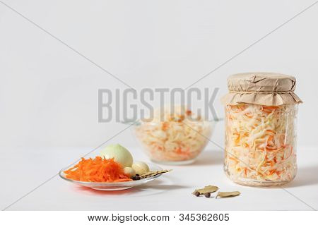 Homemade Sauerkraut With Carrots In A Glass Jar And Bowl On A White Wooden Background. Fermented Foo