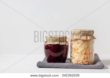 Homemade Sauerkraut With Carrots And Cabbage Salad With Beets In A Glass Jar On A White Wooden Backg