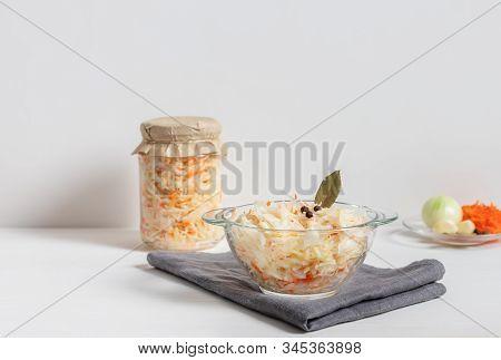 Homemade Sauerkraut With Carrots In A Glass Jar And Bowl On A White Wooden Background. Fermented Foo