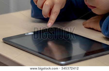 Close Up Front High View Of A Little Boy's Hand Using And Black Tablet During The Day Time