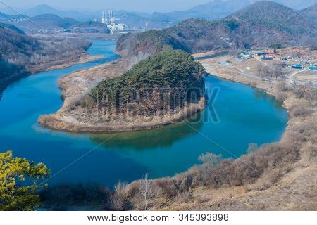 River With Beautiful Blue Water Curves Around Tree Cover Peninsula Shaped Like Korea With Factory In