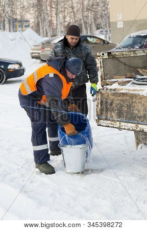 Worker Pours Water From A Barrel Into A Bucket