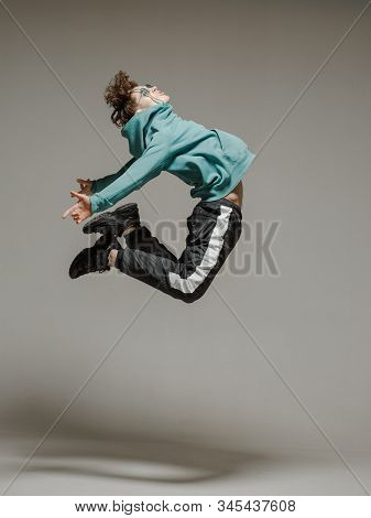 Guy Dancing Contemporary Dance In Studio. Neutral Grey Background. Acrobatic Bboy Dancer.