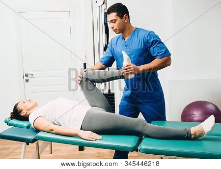 Physiotherapist Doing Leg Muscle Stretching To The Patient. Treatment Of A Womans Sciatic Nerve