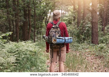 Backwards Of Man Wearing Hat, Red Sweater And Beige Trousers, Posing With Backpack And Sleeping Pad,
