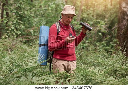 Outdoor Photo Of Man With Compass And Binovulars In Hands, Traveler On Wooden Background Wearing Red