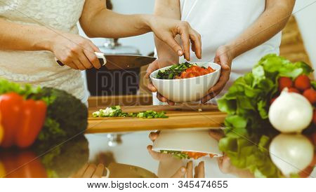 Closeup Of Human Hands Cooking In Kitchen. Mother And Daughter Or Two Female Friends Cutting Vegetab