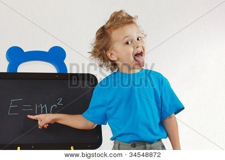 Little boy illustrato lingua come Einstein vicino formula su una lavagna