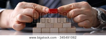 Close-up View Of Presentable Man Putting Unique Red Block On Staircase Of Other Identical Bricks. Py