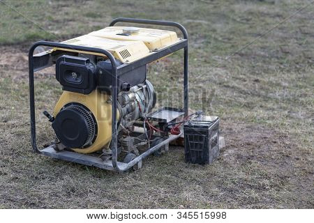 Close-up. Street Lighting. A Gasoline-powered Generator That Produces Current. A Car Battery Is Conn