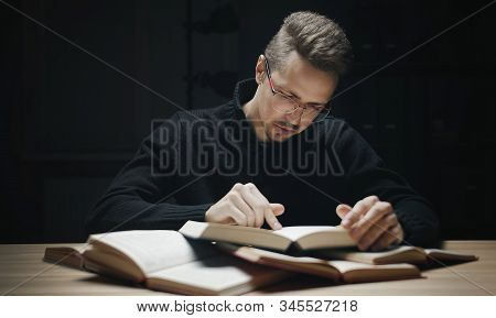 Student In Glasses Studying Among Lots Of Books Finger Tracking While Reading
