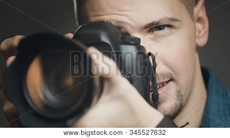 Close-up Of Photographer Looking In His Camera Viewfinder, Focus On Mans Face, Isolated Dark Backgro