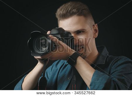 Portrait Of Photographer Holding Camera And Looking In Viewfinder, Isolated Dark Background