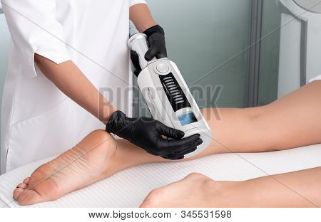 Cosmetologist In Rubber Gloves Doing Endospheres Therapy On Female Legs