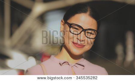Asian Middle-aged Woman Happily Smilling In Sun Rays. A Brunet Businesswoman In Glasses Laughing. Po