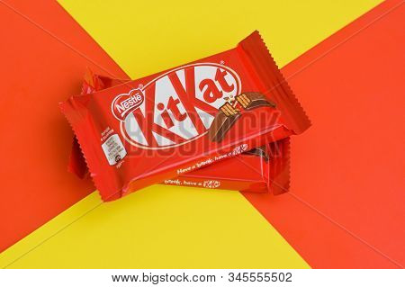 Kit Kat Chocolate Bars In Red Wrapping Lies On Yellow And Red Background. Kit Kat Created By Rowntre